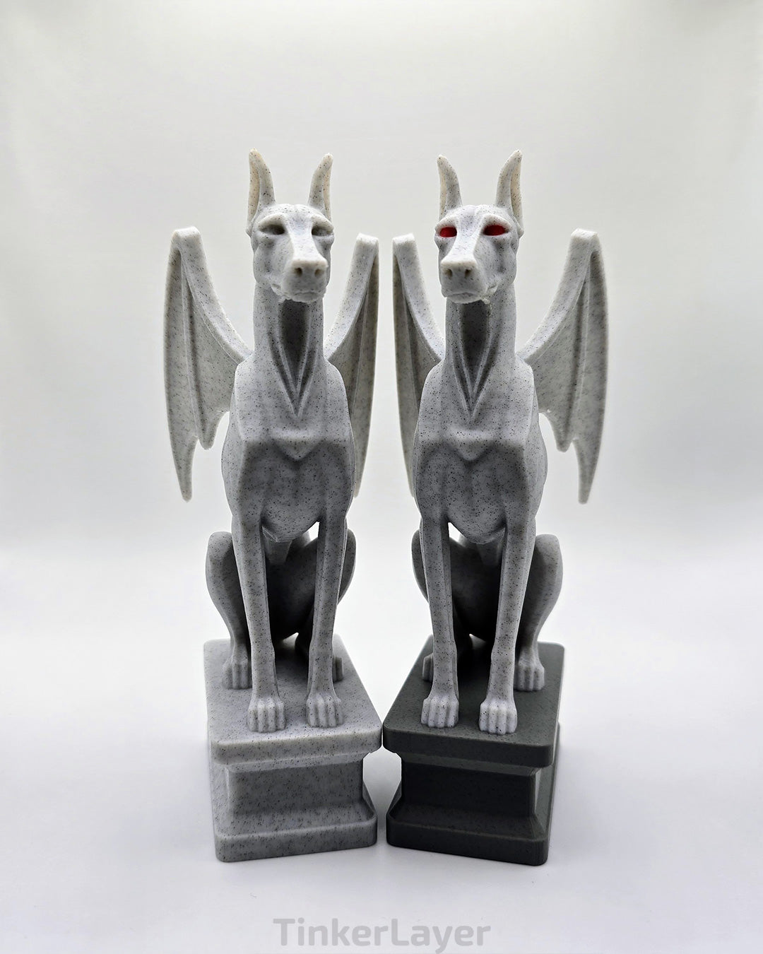 Two gothic Doberman gargoyle statues displayed side by side in marble and multicolor PLA
